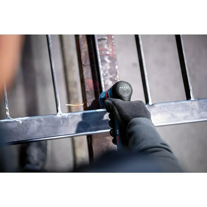 Bosch Professional Akku-Geradschleifer GWG 12V-50 S PRO SOLO - 12 V, Leerlaufdrehzahl: 5.000 U/min - 15.000 U/min - Behandschuhte Hand benutzt ein blau-schwarzes Bosch Rotationswerkzeug, um eine Metallstruktur zu schleifen, Funken erzeugend.