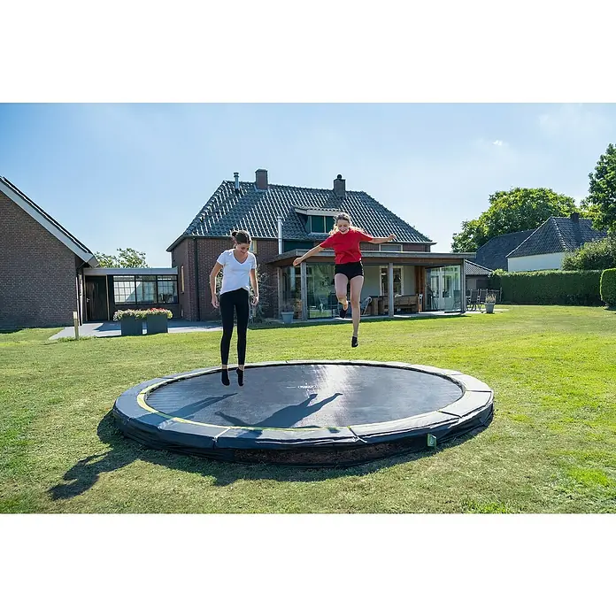Exit Toys Trampolin Silhouette Sports - Durchmesser: 427 cm, Schwarz - Zwei Frauen springen auf einem runden, schwarzen Bodentrampolin mit grünem Akzent im Garten.