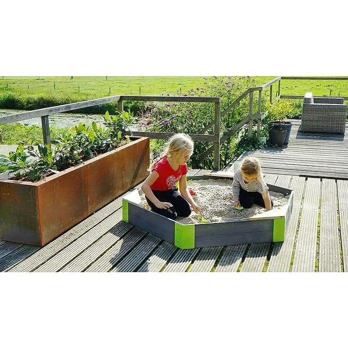 Exit Toys Sandkasten Aksent Sechseck - 160 x 140 x 21 cm, Holz, Grau - Outdoor-Sandkasten in Dunkelgrau mit hellgrünen Eckverbindern, von zwei Mädchen im Sand bespielt.