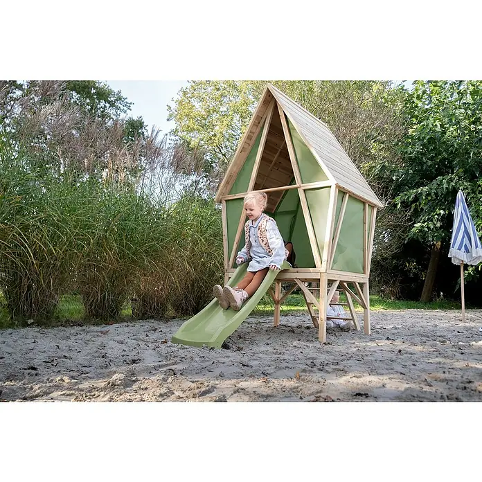 Exit Toys Spielhaus Yuki 350 - L x B x H: 256 x 148 x 219 cm, Holz, Natur/Grün - Lächelndes Kind auf einem Holzspielhaus mit grüner Rutsche, das draußen spielt.