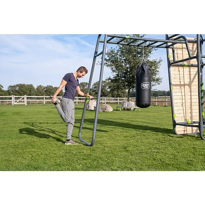 Exit Toys Turnstange GetSet MB200 / MB300 / PS500 / PS600 - Passend für: Alle GetSet Monkeybars und Powerstations, Grün - Mann dehnt sich an einem Outdoor-Klettergerüst mit schwarzem Boxsack und Holzkletterwand.