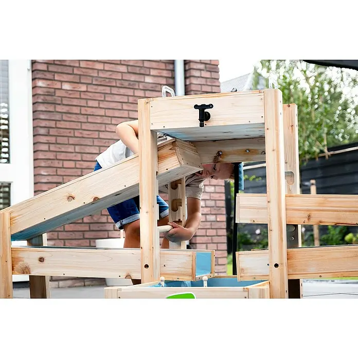 Exit Toys Wasserbahn Aquaflow - Holz, Natur/Blau, 221 x 73 x 90 cm - Hölzerner Wasser-Spieltisch mit blauen Kanälen und schwarzem Hahn, ein Kind interagiert damit.