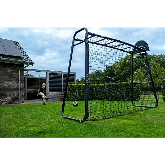 Exit Toys Fußballtor GetSet Fußballnetz MB200 - Passend für: GetSet Monkeybar MB200, 250 x 234 cm, Schwarz - Ein Kind tritt einen grün-schwarzen Fußball auf ein schwarzes Fußballtor mit Netz in einem Garten.