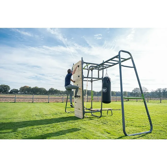 Exit Toys Kletterwand GetSet PS500 / PS600 - Passend für: Alle GetSet Powerstations, 116 x 275 cm - Mann klettert an einer Holzkletterwand, Teil eines grauen Outdoor-Fitnessgeräts mit Monkey Bars und Boxsack.