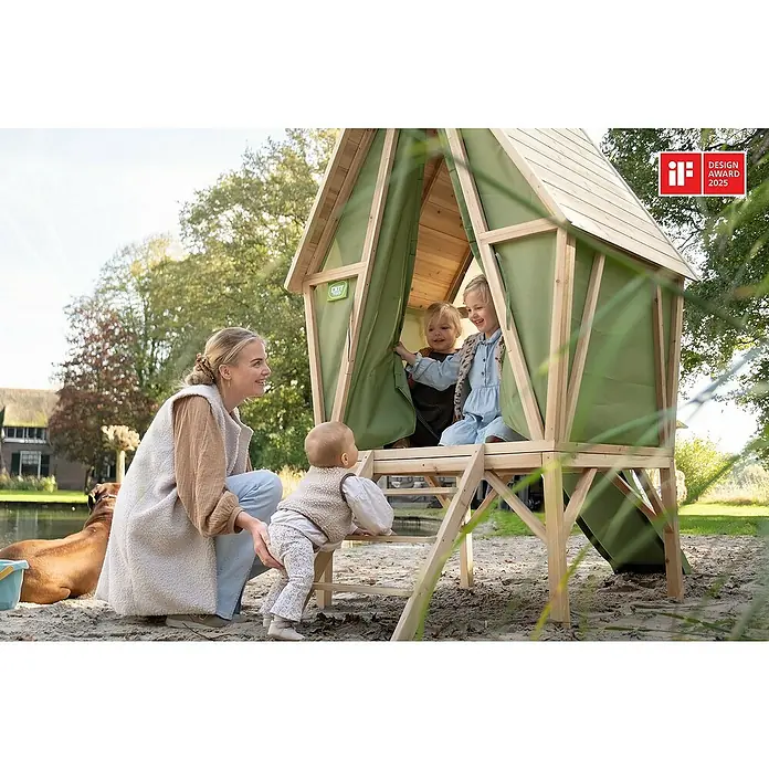 Exit Toys Spielhaus Yuki 300 - L x B x H: 226 x 124 x 219 cm, Holz, Natur/Grün - Kinder spielen in und um ein erhöhtes Holzspielhaus mit grünen Stoffwänden und einer Leiter. Ein Erwachsener hilft einem Baby beim Hochklettern.
