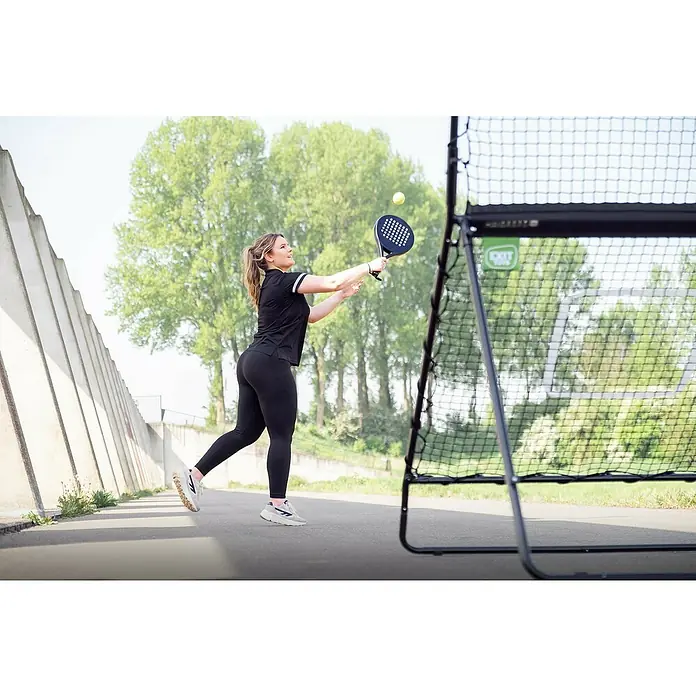 Exit Toys Sportnetz Smash Padel Rebounder - 164 x 124 x 202 cm, Stahl, Schwarz - Frau in schwarzer Sportkleidung schlägt einen Tennisball mit einem Padel-Schläger gegen ein schwarzes Exit Toys Netz.