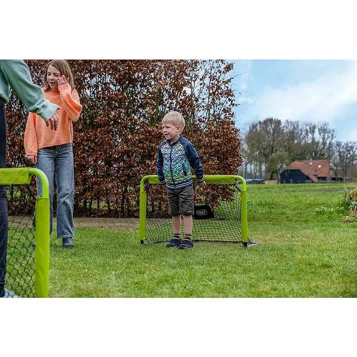 Exit Toys Fußballtor Tempo 900 Mini - 2 Stk., B x H: 90 x 60 cm, Grün/Schwarz - Ein kleines Kind steht hinter einem grünen Mini-Fußballtor auf einer Grasfläche.
