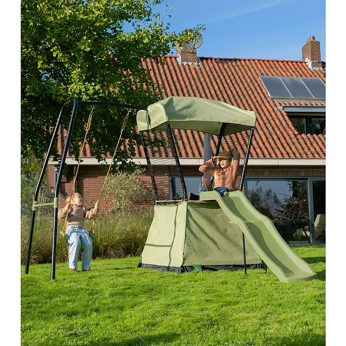 Exit Toys Spielhaus Ivy - L x B x H: 253 x 268 x 216 cm, Holz, Grün/Schwarz, Mit Rutsche und Schaukel - Zwei Kinder spielen auf einem grünen und schwarzen Schaukelgerüst mit Spielturm und Rutsche in einem sonnigen Garten.