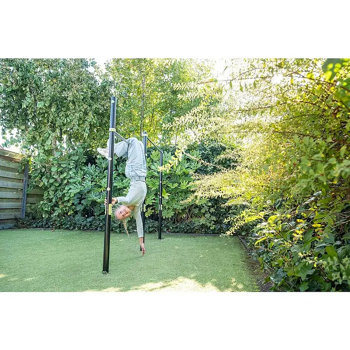 Exit Toys Turnstange Ivy - B x H: 225 x 154 cm, Doppel, Stahl - Mädchen hängt kopfüber an einer schwarzen Calisthenics-Stange mit grünen Akzenten, auf grünem Rasen.
