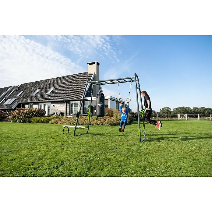 Exit Toys Klettergerüst GetSet Monkeybar MB230 - 442 x 125 x 248 cm, Stahl, Grau - Grau-grünes Outdoor-Multigym mit Boxsack, Ringen und Dip-Barren, von Erwachsenem und Kind im Garten genutzt.