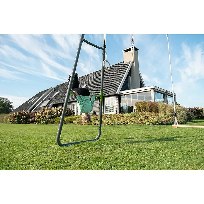 Exit Toys Klettergerüst GetSet Monkeybar MB210 - 331 x 115 x 248 cm, Stahl, Grau - Kind hängt kopfüber an einer grünen Stange eines grauen Metall-Spielgeräts.