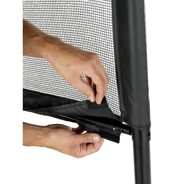 Exit Toys Sportnetz - Höhenverstellbar, 500 x 243 cm, Stahl - Hände befestigen ein schwarzes Sicherheitsnetz mit Klettverschlüssen an einer schwarzen Stützstange.