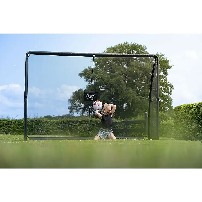 Exit Toys Fußballtor Finta - 300 x 200 cm, Mit Torwand, Schwarz - Kind wirft Fußball auf schwarzes EXIT TOYS Tor/Rebounder Netz im Garten.