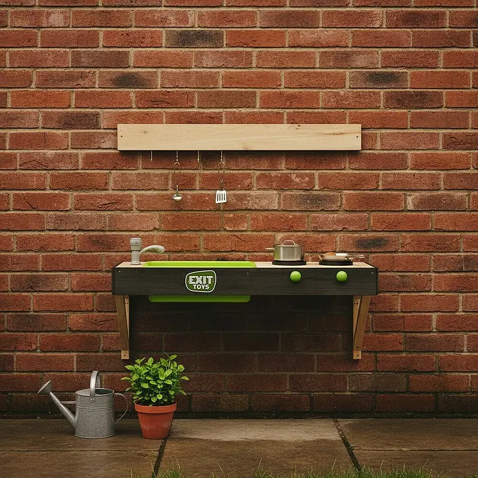 Exit Toys Matschküche Yummy 50 - 34 x 90 x 35 cm, Holz, Natur - Dunkelgraue und naturfarbene Kindermatschküche aus Holz mit grünen Akzenten, Spüle, Herdplatte und hängenden Utensilien, an einer Ziegelwand montiert.