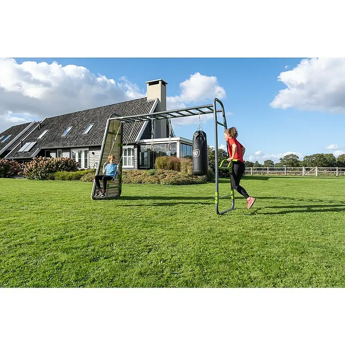 Exit Toys Klettergerüst GetSet Monkeybar MB320 - 400 x 125 x 248 cm, Stahl, Grau - Graues Metall-Klettergerüst mit grünen Akzenten, Jungen auf Holzschaukel, Boxsack, Ringen und Frau an Dip-Barren im Freien.