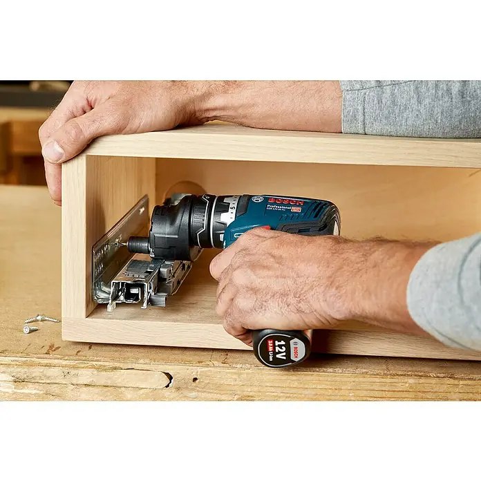 Bosch Professional AMPShare 18V Akku-Bohrschrauber-Set GSR 12V-35 FC - 12 V, 2 Akkus, 35 Nm, 12 -tlg. - Eine Person verwendet einen blau-schwarzen Bosch Akkuschrauber, um Metallschubladenschienen in einem hellen Holzschrank zu montieren.