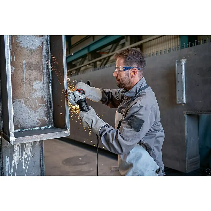 Bosch Professional Elektro-Winkelschleifer GWS 17-125 PSB - 1.700 W, Durchmesser Scheibe: 125 mm, Leerlaufdrehzahl: 2.800 U/min - 11.500 U/min - Mann in Schutzkleidung benutzt einen grau-schwarzen Winkelschleifer mit rotem Akzent, um einen Metallträger zu schleifen und Funken zu erzeugen.