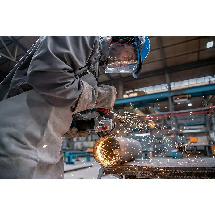 Bosch Professional Elektro-Winkelschleifer GWS 17-125 PSB - 1.700 W, Durchmesser Scheibe: 125 mm, Leerlaufdrehzahl: 2.800 U/min - 11.500 U/min - Arbeiter in Schutzkleidung schneidet Metallrohr mit Winkelschleifer, erzeugt Funken. Trägt Gesichtsschild und Handschuhe.