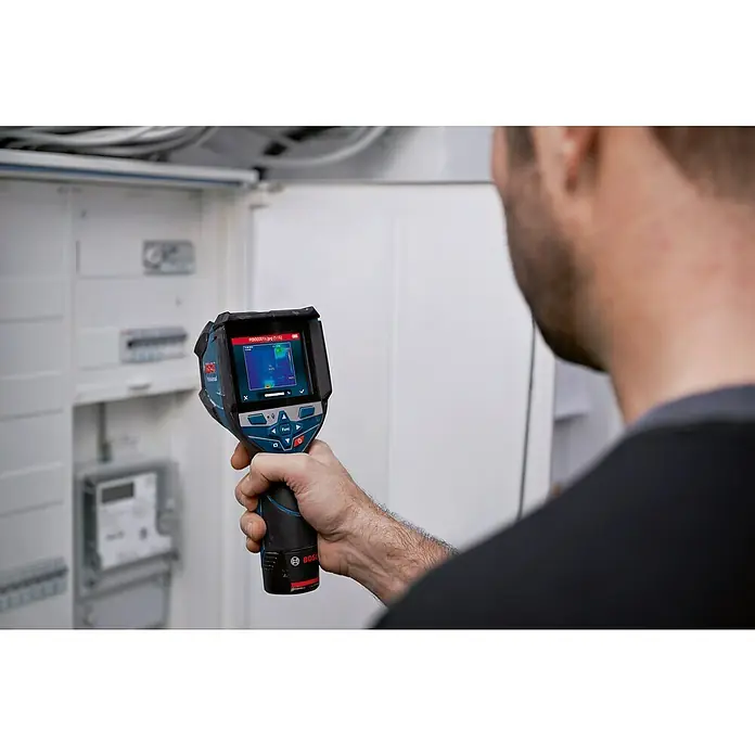 Bosch Professional Wärmebildkamera GTC 600 C PRO - Messbereich Temperatur: -20 °C - 600 °C - Blaue und schwarze Bosch Wärmebildkamera, von einer Person gehalten, zeigt ein Wärmebild eines Schaltkastens.