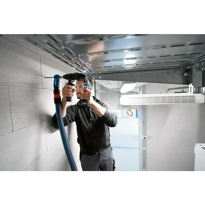 Bosch Professional AMPShare 18V Akku-Bohrschrauber-Set GSR 12V-35 FC - 12 V, 2 Akkus, 35 Nm, 12 -tlg. - Mann bohrt mit einem blau-schwarzen Bohrer und blauer Staubabsaugung in eine weiße Wand unter Kabeltrassen.