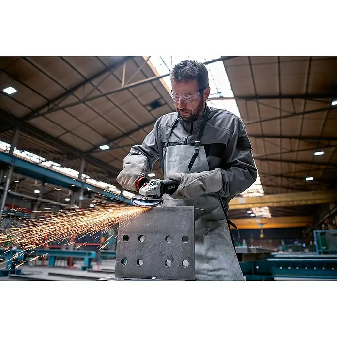 Bosch Professional Elektro-Winkelschleifer GWS 17-125 PSB - 1.700 W, Durchmesser Scheibe: 125 mm, Leerlaufdrehzahl: 2.800 U/min - 11.500 U/min - Mann in Schutzkleidung schleift Metallplatte mit Winkelschleifer, erzeugt helle Funken.