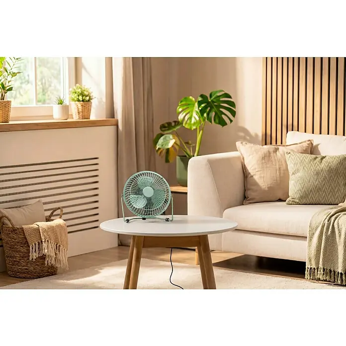 Voltomat USB-Ventilator Mini - Grün, 18 cm - Ein mintgrüner Metall-Tischventilator auf einem hellen Couchtisch in einem sonnigen Wohnzimmer.