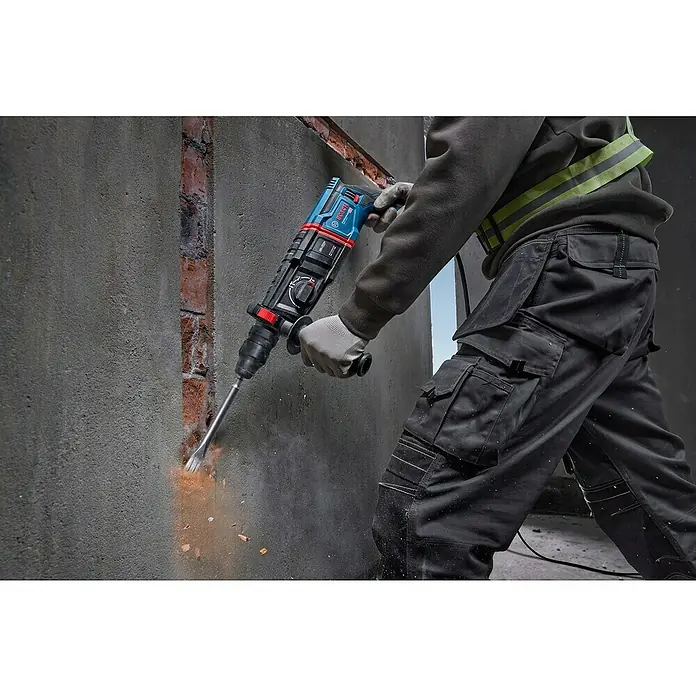 Bosch Professional Bohrhammer-Set GBH 2-26 F - 2,7 J - Blauer und schwarzer Bosch Bohrhammer im Einsatz, der Beton von einer Wand abschlägt.