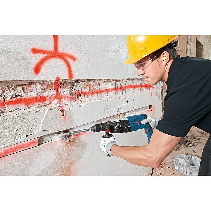 Bosch Professional Bohrhammer GBH 2-28 F - 880 W, 3,2 J, SDS-Plus-Aufnahme - Eine Person nutzt einen blau-schwarzen Boschhammer Bohrhammer zum Meißeln in eine Wand.