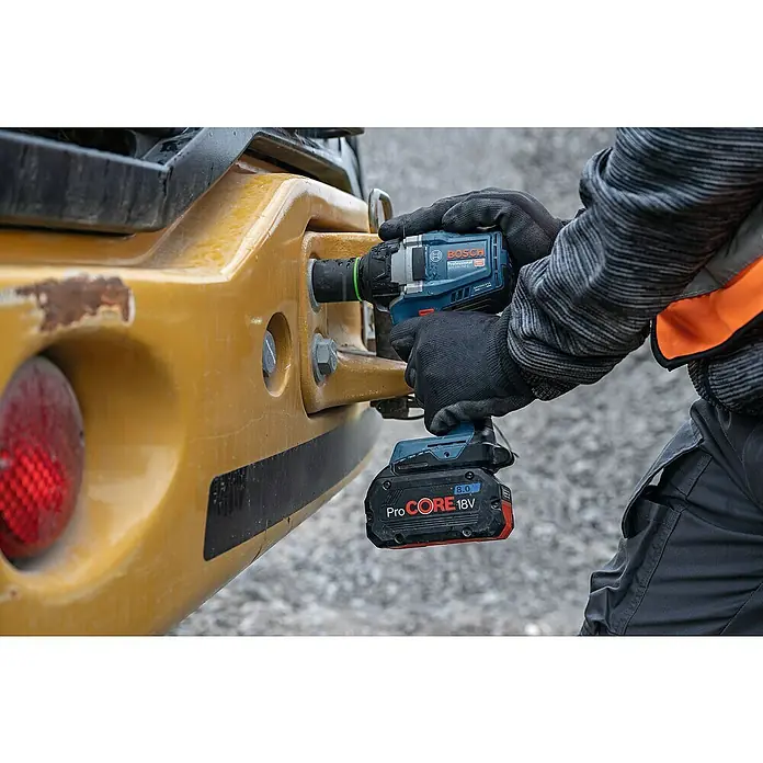 Bosch Professional AMPShare 18V Akku-Drehschlagschrauber GDS 18V-750 C - 18 V, Ohne Akku - Person benutzt blauen Bosch Schlagschrauber mit 8.0 Ah ProCORE 18V Akku an gelber Baumaschine.