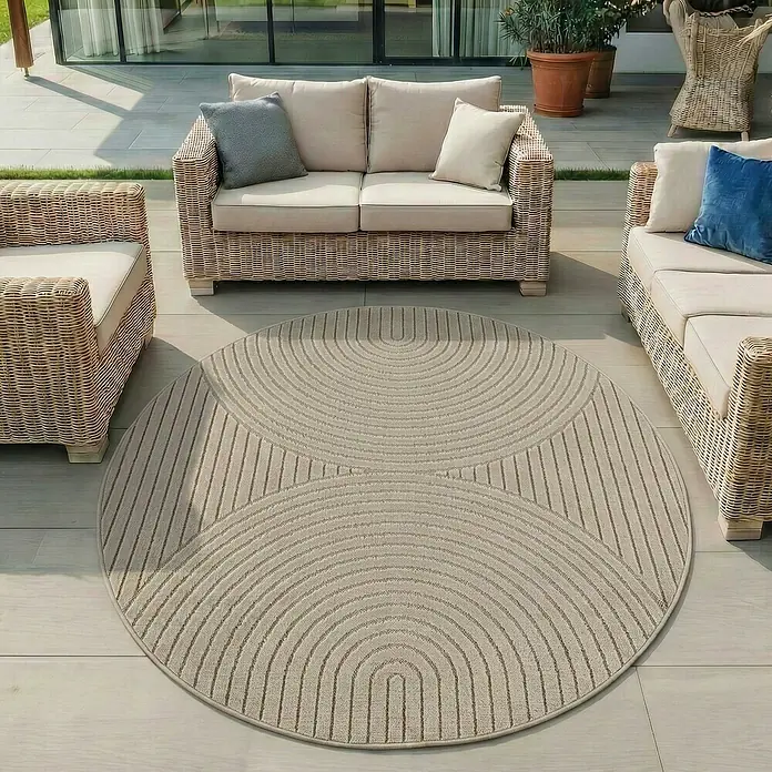 Outdoor-Teppich Nova I - Beige, Durchmesser: 80 cm, 100 % Polypropylen - Runder beiger Outdoor-Teppich mit konzentrischem Bogen- und Streifenmuster auf einer Terrasse.