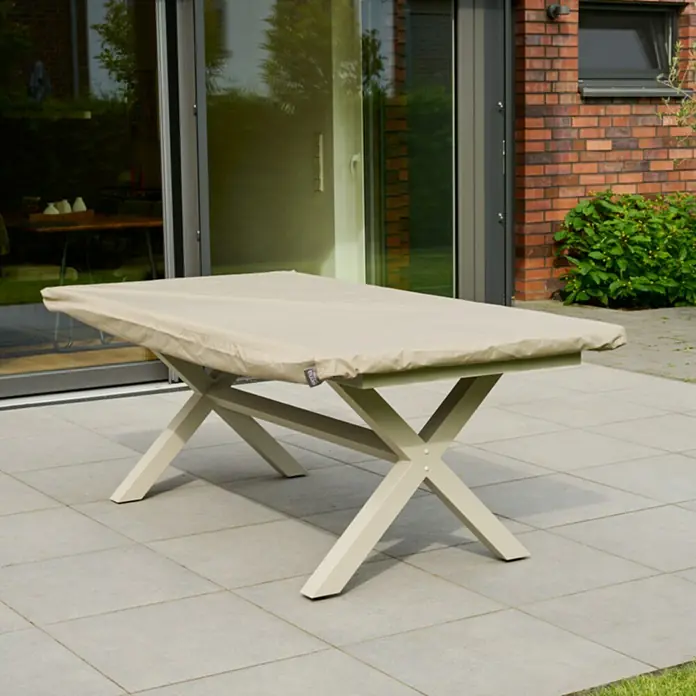 Siena Garden Gartentisch-Schutzhülle PLUS - L x B x H: 220 x 110 x 15 cm, Polyester, TPU laminiert, Beige - Beige Schutzhülle auf einem Gartentisch mit beigefarbenem Kreuzbein-Untergestell auf einer Terrasse.