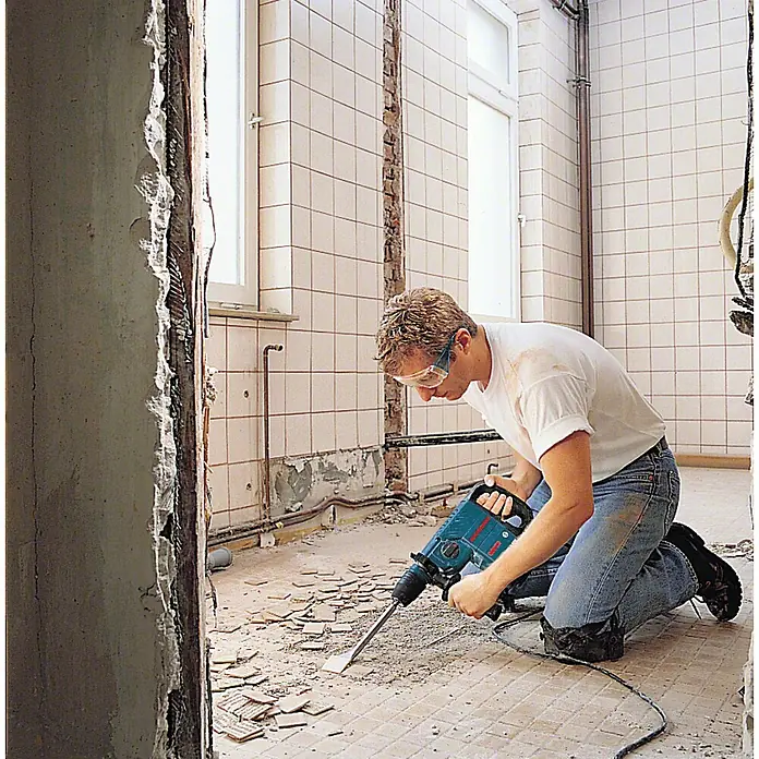 Bosch Professional Abbruchhammer GSH 3 - 650 W, 2,6 J, SDS-Plus-Aufnahme - Mann mit Schutzbrille nutzt blauen Abbruchhammer zum Entfernen von Bodenfliesen.