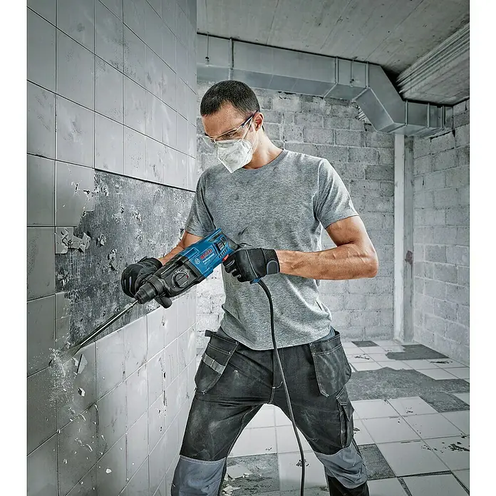 Bosch Professional Bohrhammer GBH 2-21 - 720 W, 2 J, SDS-Plus-Aufnahme - Mann in Schutzkleidung verwendet einen blauen Bosch Professional Bohrhammer zum Entfernen von Fliesen.