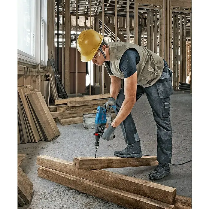 Bosch Professional Bohrhammer GBH 2-21 - 720 W, 2 J, SDS-Plus-Aufnahme - Blauer Bosch Bohrer, von einem Mann zum Bohren in einen Holzbalken verwendet.