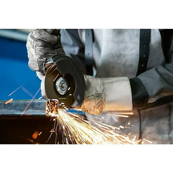 Bosch Professional Elektro-Winkelschleifer GWS 12-125 - Durchmesser Scheibe: 125 mm, Leerlaufdrehzahl: 0 U/min - 11.000 U/min - Eine Person in Schutzkleidung benutzt einen Bosch Winkelschleifer zum Trennen von Metall, wodurch helle Funken entstehen.