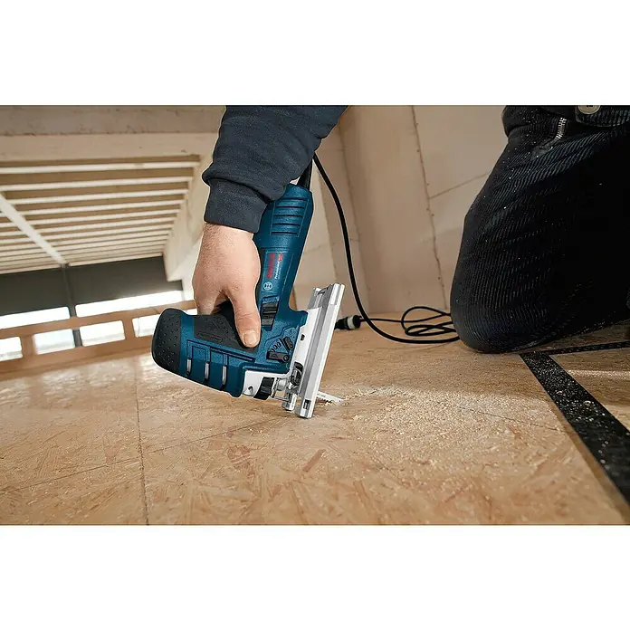 Bosch Professional Elektro-Stichsäge GST 150 CE - 500 /min - 3.100 /min, 150 mm - Blaue und schwarze Bosch Professional Stichsäge wird von einer Hand gehalten und schneidet Holz, mit sichtbarem Sägemehl.