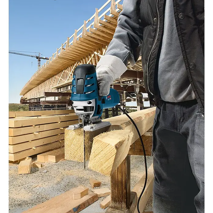 Bosch Professional Elektro-Stichsäge GST 150 CE - 500 /min - 3.100 /min, 150 mm - Blau-schwarze Bosch Stichsäge schneidet einen Holzbalken auf einer Baustelle.