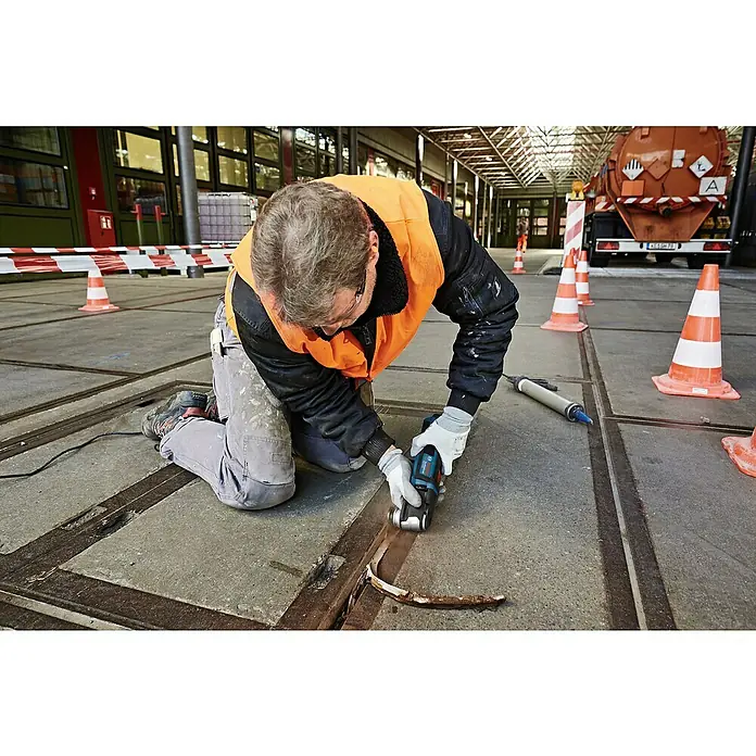 Bosch Professional Elektro-Multifunktionswerkzeug GOP 55-36 - 550 W, Oszillationswinkel: 1,8 ° - Ein Arbeiter verwendet ein blau-schwarzes Bosch-Oszillierwerkzeug an einer Betonfugen.