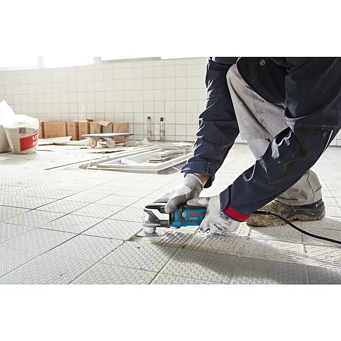 Bosch Professional Elektro-Multifunktionswerkzeug GOP 55-36 - 550 W, Oszillationswinkel: 1,8 ° - Eine Person verwendet ein blau-schwarzes Bosch Professional Multifunktionswerkzeug auf Bodenfliesen.
