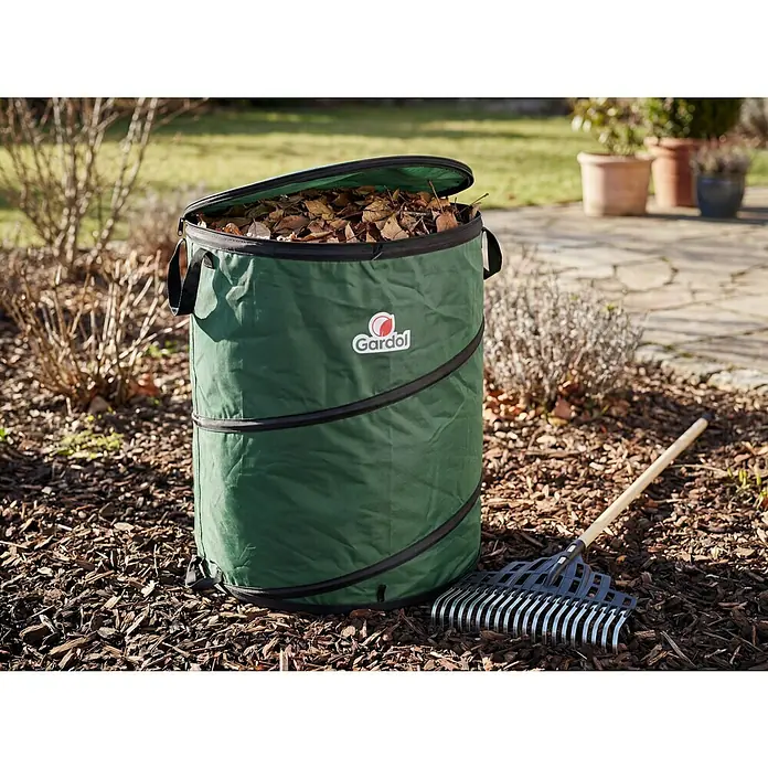 Gardol Premium Pop-Up Gartenabfallsack - 175 l, Ø x H: 56 x 71 cm - Dunkelgrüner, zusammenklappbarer Gardol Gartenabfallsack gefüllt mit Laub, daneben ein Rechen im Garten.