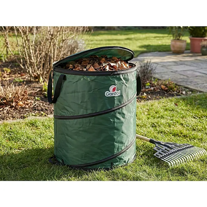 Gardol Premium Pop-Up Gartenabfallsack - 150 l, Ø x H: 56 x 61 cm - Grüner faltbarer Gartenabfallsack, gefüllt mit Laub, neben einem Rechen auf Rasen.