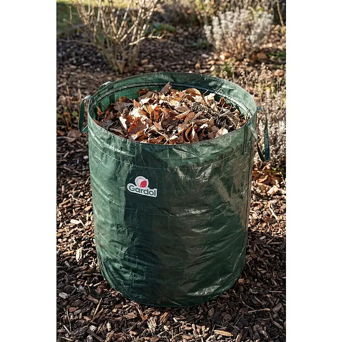 Gardol Gartenabfallsack - 350 l, Höhe: 90 cm, Durchmesser: 70 cm - Grüner Gardol Gartenabfallsack, gefüllt mit trockenen Blättern, im Garten auf Rindenmulch.