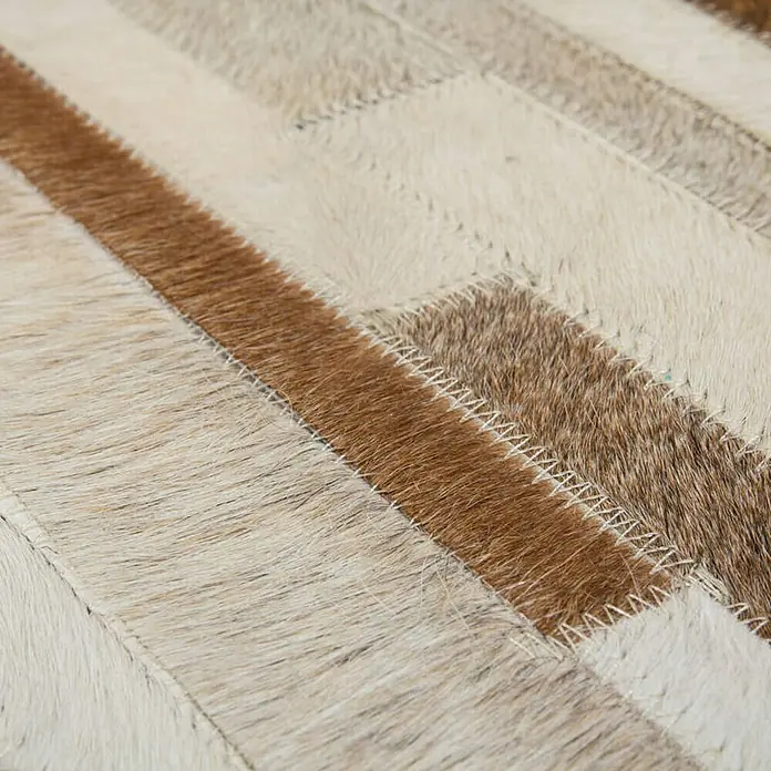 Kayoom Lederteppich Eclipse 110 - Creme/Braun, 170 x 120 cm, 100 % Leder - Detailaufnahme eines Teppichs aus Kuhfell-Patchwork in Braun- und Beigetönen mit Zickzack-Nahtmuster.