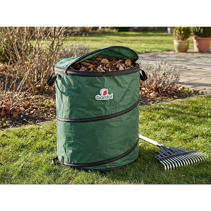 Gardol Premium Pop-Up Gartenabfallsack - 80 l, Ø x H: 46 x 48 cm - Grüner faltbarer Gartensack voller Blätter, mit einem Rechen daneben im Garten.