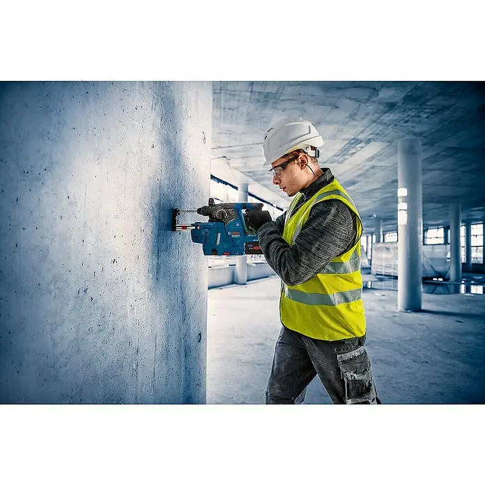 Bosch Professional AMPShare 18V Akku-Kombihammer GBH 18V-24 C - 18 V, Ohne Akku, 2,4 J - Arbeiter bohrt mit blauem Bosch Bohrhammer und Staubabsaugung in eine Betonwand.