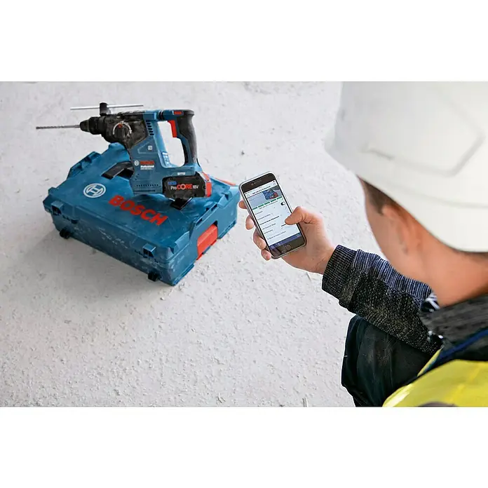 Bosch Professional AMPShare 18V Akku-Kombihammer GBH 18V-24 C - 18 V, Ohne Akku, 2,4 J - Blauer Bosch Akku-Bohrhammer auf seinem Koffer, von einem Arbeiter mit Schutzhelm per Smartphone-App verbunden.
