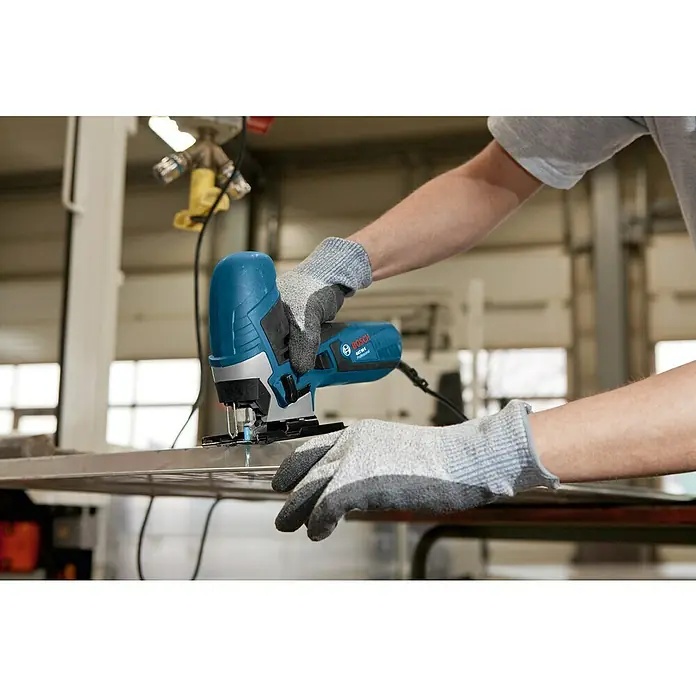 Bosch Professional Elektro-Stichsäge GST 90 E - 500 /min - 3.100 /min - Eine Person sägt mit einer blau-schwarzen Bosch Stichsäge ein Metallblech in einer Werkstatt.