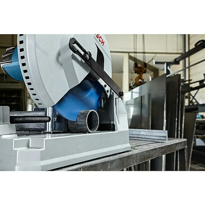 Bosch Metallkreissäge GCD 12 JL - 2.000 W, Leerlaufdrehzahl: 1.500 U/min - Eine graue und blaue Bosch Trennsäge schneidet ein Metallrohr in einer Werkstatt. Blaue Trennscheibe sichtbar.