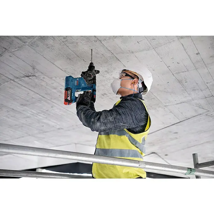 Bosch Professional AMPShare 18V Akku-Kombihammer GBH 18V-24 C - 18 V, Ohne Akku, 2,4 J - Arbeiter bohrt mit blauem Bosch 18V Bohrhammer und Akku in eine Betondecke.
