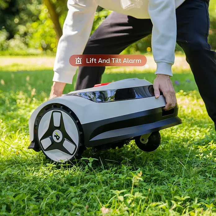 RoboUp Mähroboter Raccoon 2 SE - 600 m², Schnittbreite: 20 cm, Kamera-gestützte Navigation - Person hebt grauen und schwarzen Mähroboter vom Rasen, zeigt Hebe- und Kippalarmfunktion.